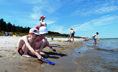 Kinder spielen am Strand mit Schaufeln und Eimern