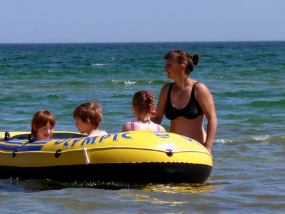 Drei Kinder sitzen im Schlauchboot und werden von der Betreuerin geschoben