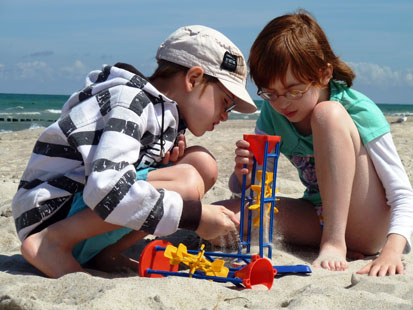 Ein Mädchen und ein Junge spielen im Sand mit Sandspielsachen
