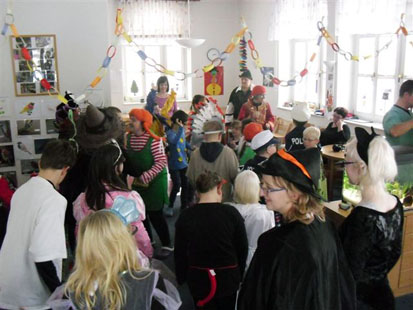 Viele verkleidete Kinder stehen in einem bunt geschmückten Raum.