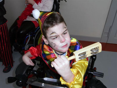Ein Junge, verkleidet als Clown, spielt mit einer Rassel.