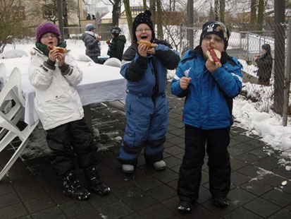 Die Kinder haben viel Spaß mit ihrer Bratwurst.