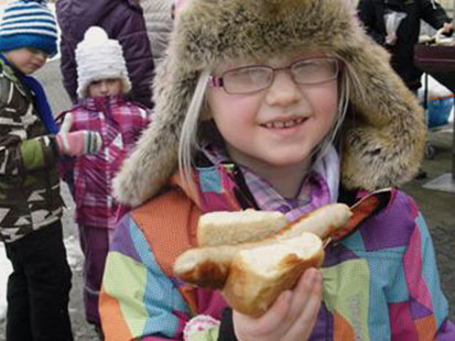 Ein Mädchen zeigt ihre Bratwurst.