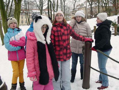 Sechs Kinder stehen im Schnee und warten.