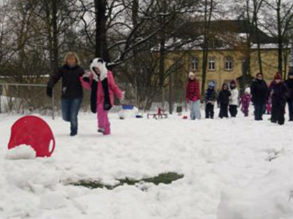 Eine Betreuerin führt ein Kind zur roten Schneeschüssel.