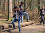 Die Kinder springen auf dem Spielplatz über einen sich drehenden Stamm.