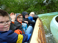 Vier Kinder sitzen in einem Boot in der Wildwasserbahn.