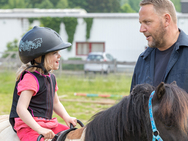 Ein kleines Mädchen reitet auf einem Pony.