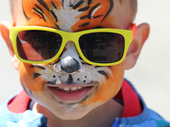 Wie ein Tiger geschminkter Junge mit Sonnenbrille