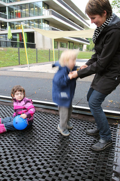 Erzieherin springt mit blondem Kind auf dem Trampolin