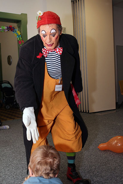 Der Clown reicht einem Kind die Hand.