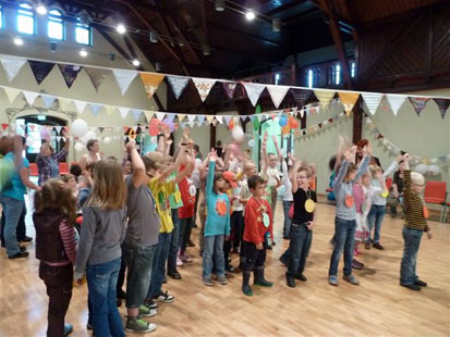 Viele Kinder stehen im geschmückten Saal und melden sich