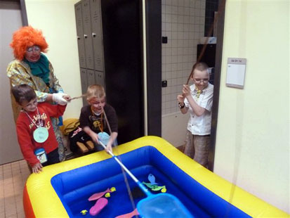 3 Kinder und ein Clown angeln im Planschbecken