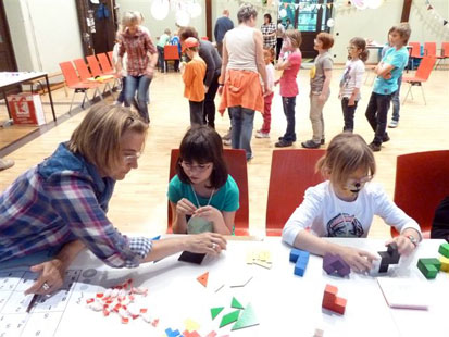 3 Kinder spielen mit bunten Bausteinen auf dem Tisch