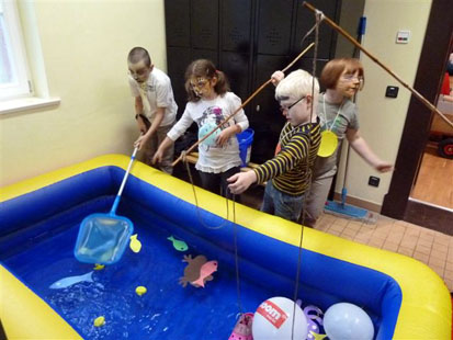Kinder versuchen, Spielfische aus einem Planschbecken zu angeln