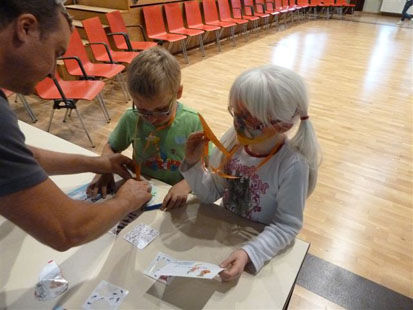 Ein Betreuer hilft zwei Kindern beim Bastel