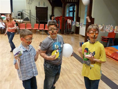 3 Kinder mit geschminkten Gesichtern und Luftballons
