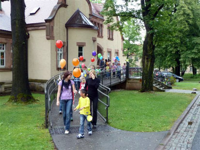 Kinder mit Luftballon kommen aus dem Haus