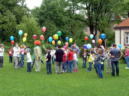 Kinder mit Luftballon stehen auf der Wiese
