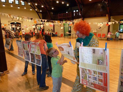 Ein Kind hängt mit dem Clown Zeitungen auf