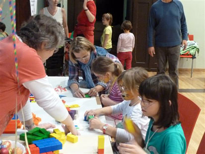 Kinder sitzen am Tisch und spielen mit bunten Steinen